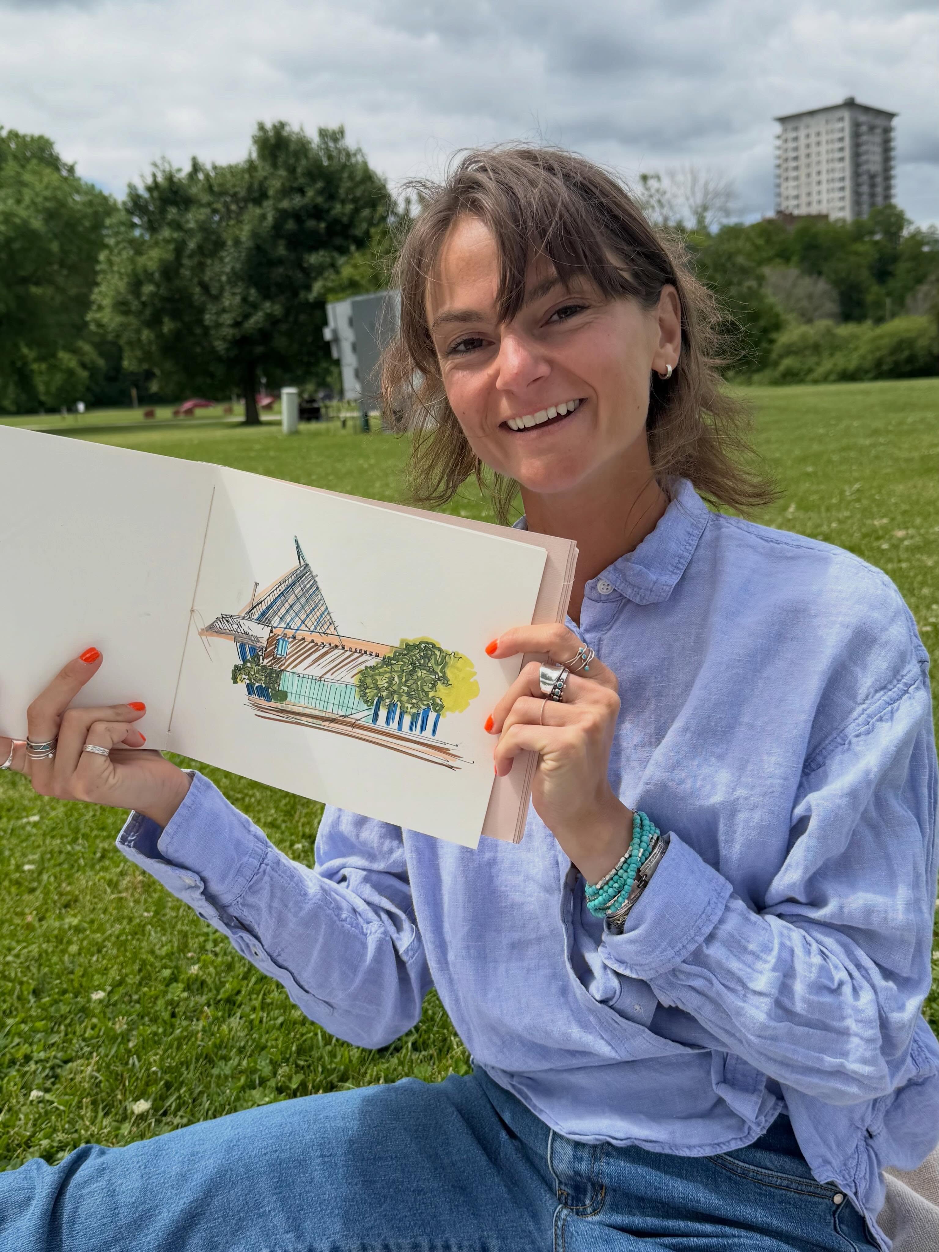 Jordy Schmidt outdoors in Milwaukee, holding a colorful piece of her original artwork